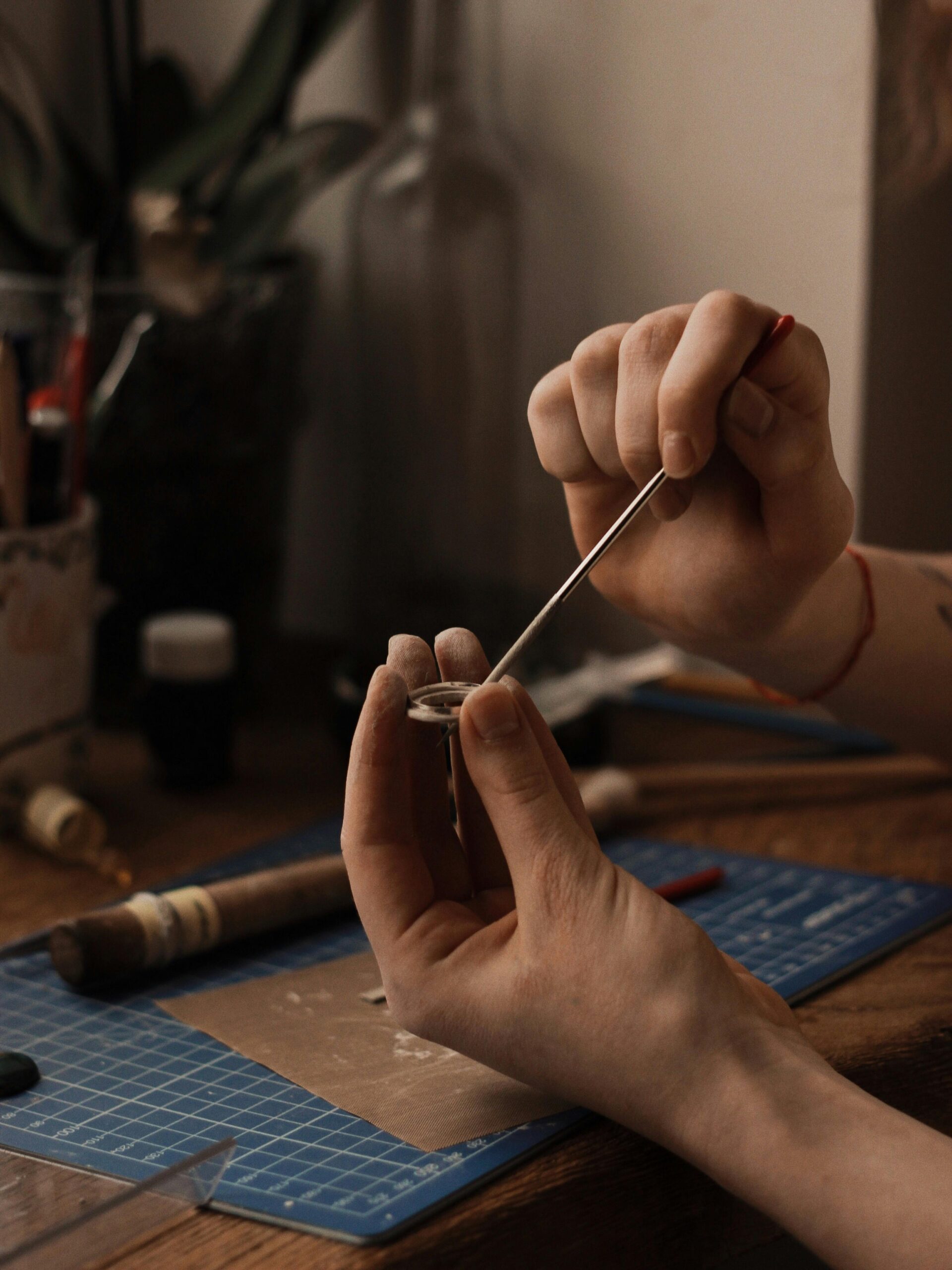 Close-up of a jeweler crafting handmade jewelry on a workbench using tools and silver.